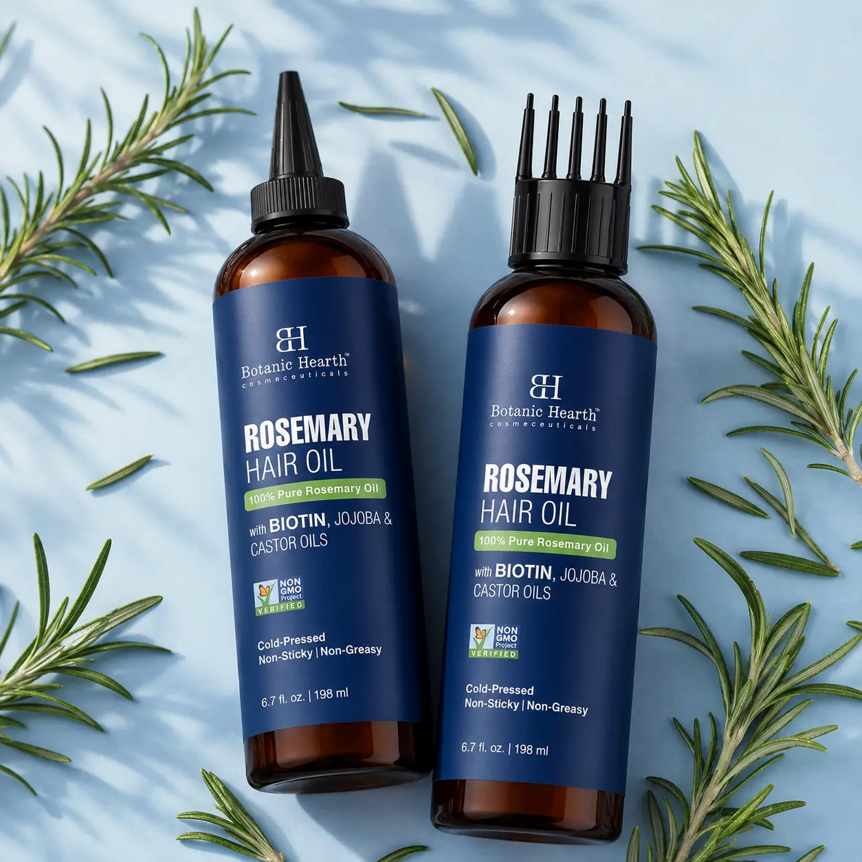 Flat-lay of hair growth oil bottles showing nozzle and comb applicator options with fresh rosemary leaves