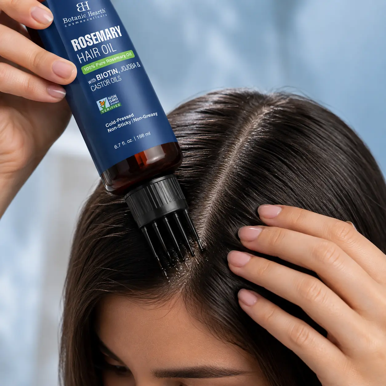 Woman applying hair growth oil directly to the scalp using the comb applicator for precise root coverage.
