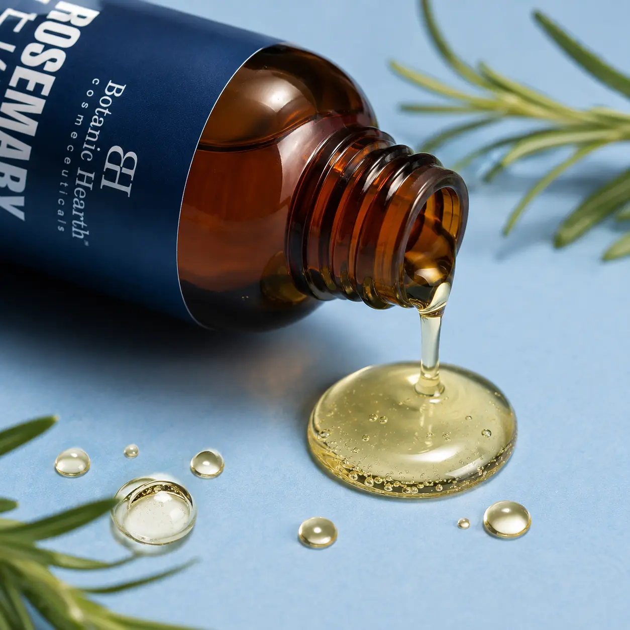 Close-up of hair growth oil pouring a clear golden oil drop, highlighting its lightweight non-greasy texture.